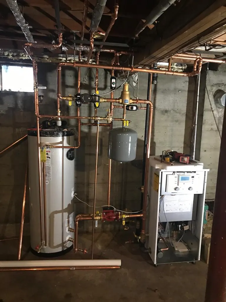 Hot water tank in a utility room with copper supply lines and valves, the area to check first when a water heater starts leaking